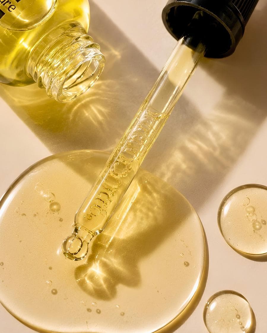 Pipette de sérum qui dépose une goutte d’huile dorée